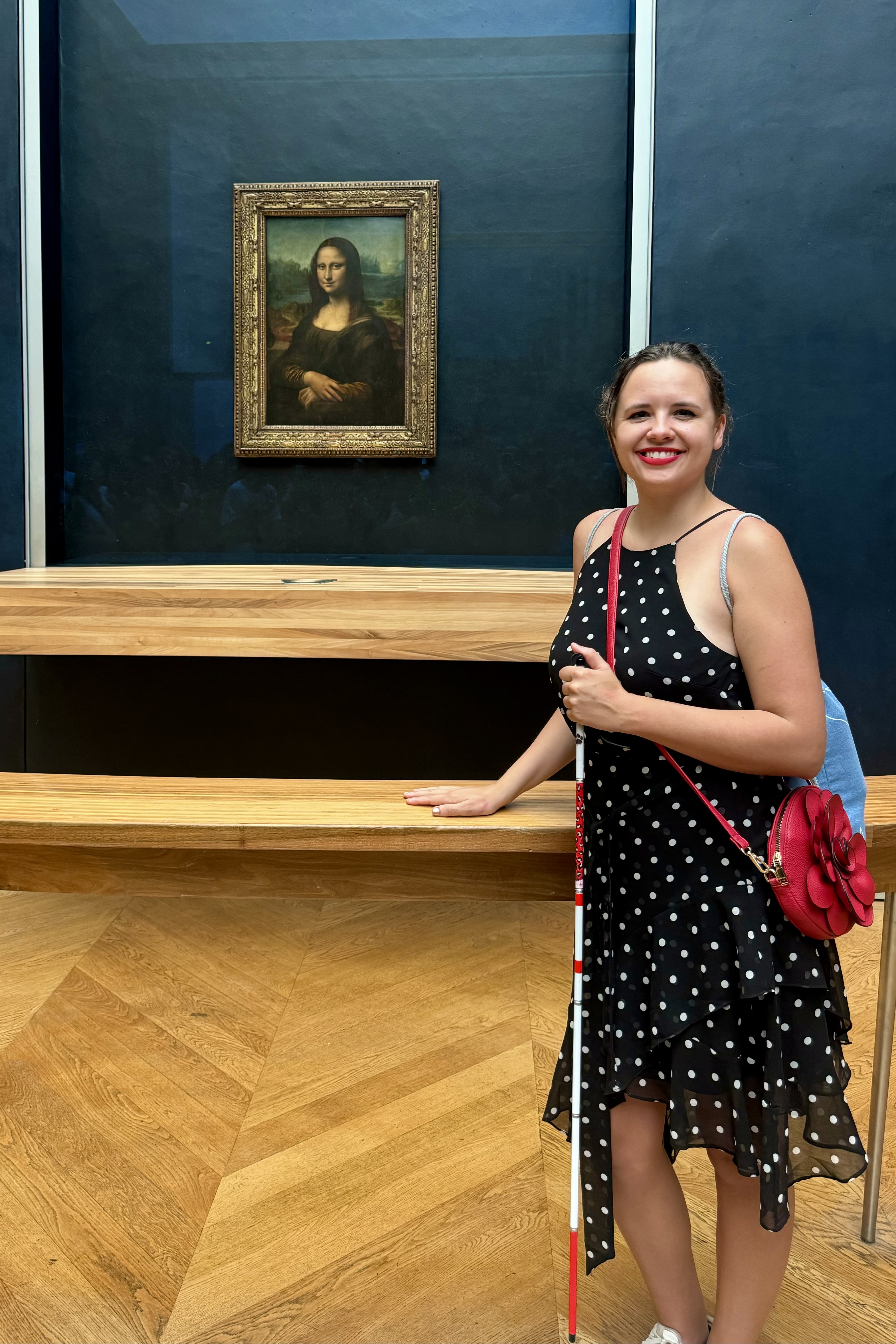 Marie Elise staat bij de Mona Lisa. Ze heeft haar taststok vast.