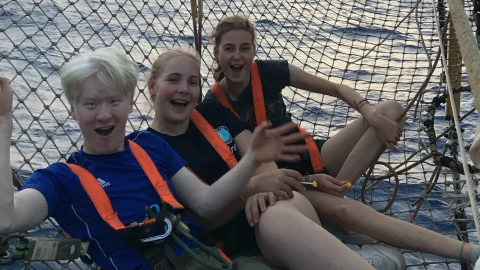 Jing met z'n crew hangend in een net aan de voorkant van de boot