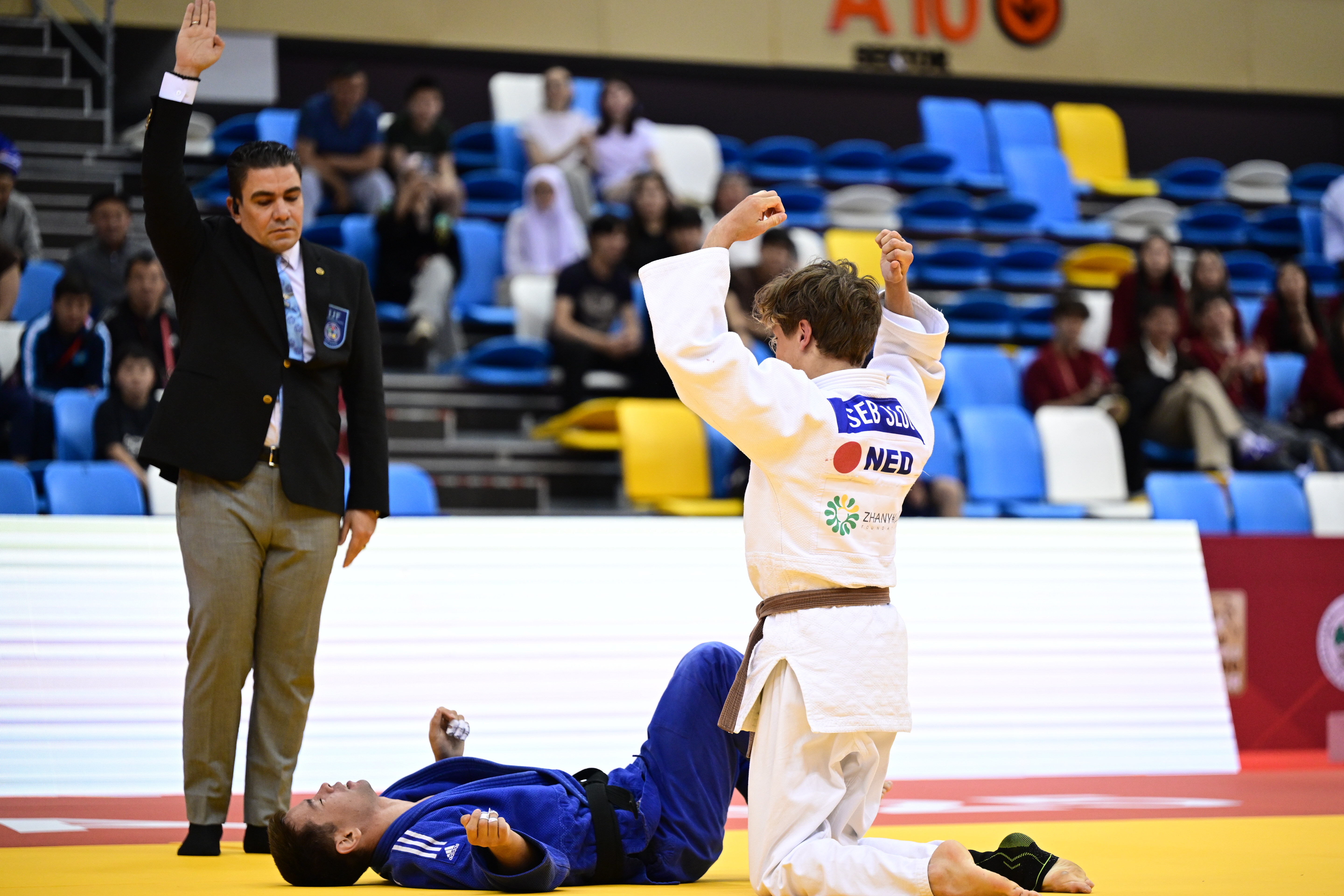 Judoka Seb Sloot zit op de judomat en maakt een krachtige beweging na de overwinning op zijn tegenspeler