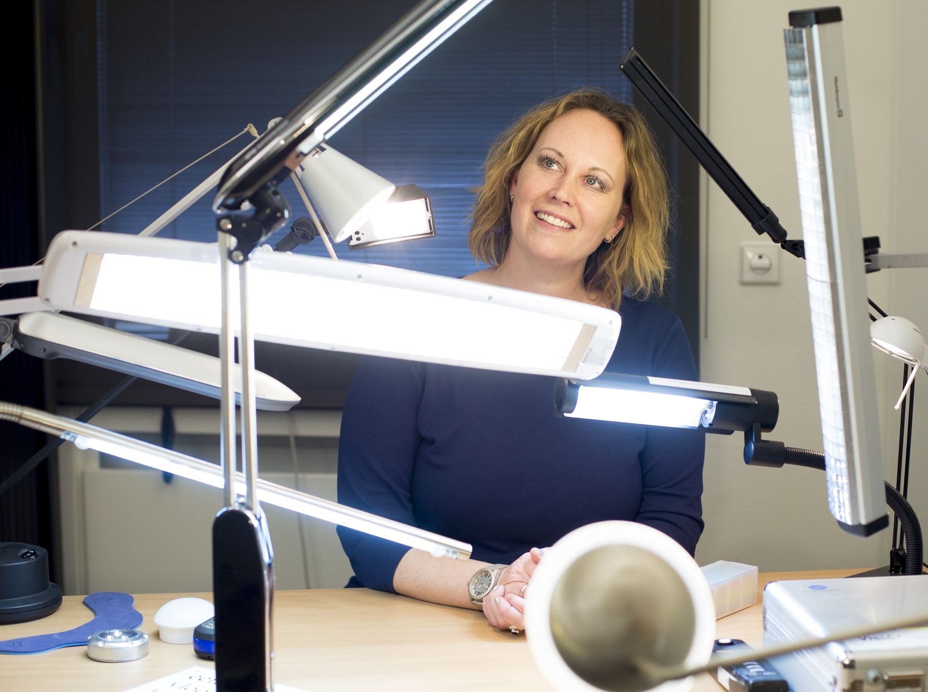 Portretfoto van Frouck de Boer die met diverse lampen en hulpmiddelen aan een tafel poseert en schuin wegkijkt van de camera.