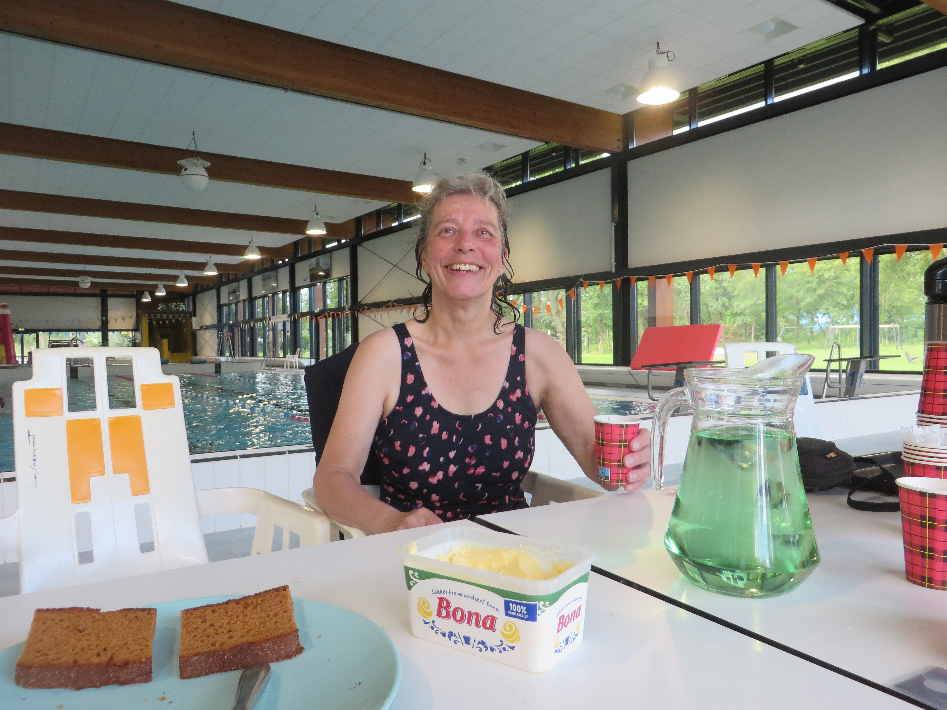 Sylvia de Nijs zit aan tafel in een binnenzwembad tijdens de Nationale Zwemvierdaagse 2024