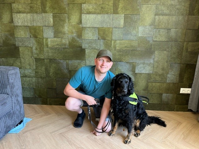 Theo van der Linden in zomerse wandelkleding met zijn zwarte geleidehond