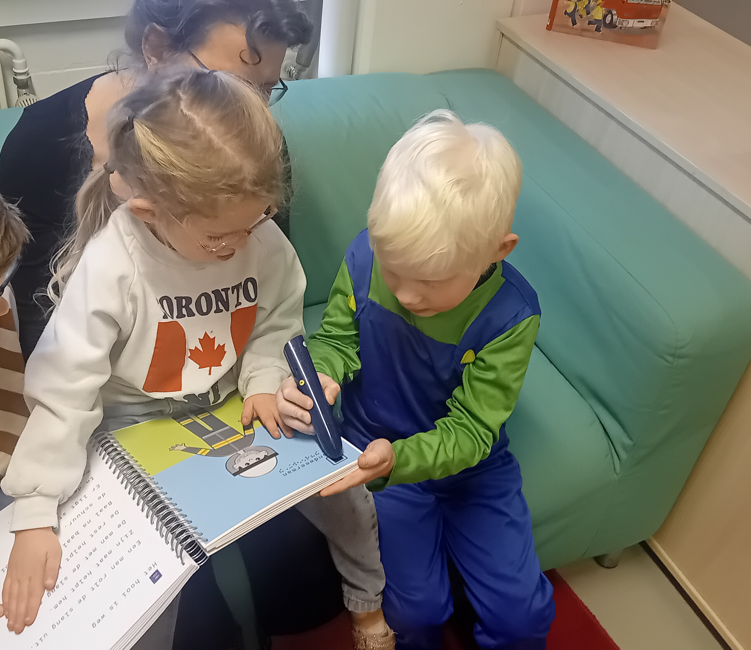 Een jongen en meisje van de kleuterdagrevalidatiegroep bij Visio testen een Samenleesboek