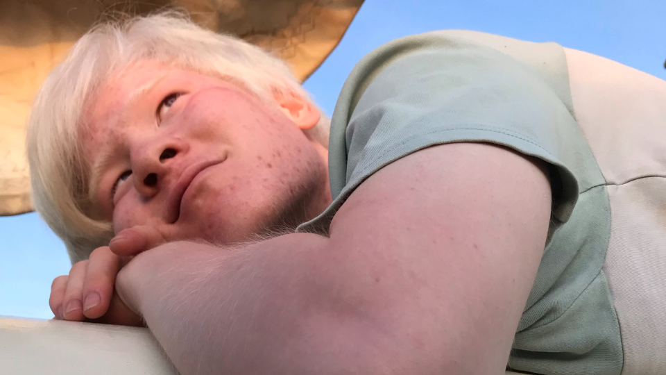 Jing ligt op de rand van de boot en kijkt naar de lucht, terwijl de zon onder gaar