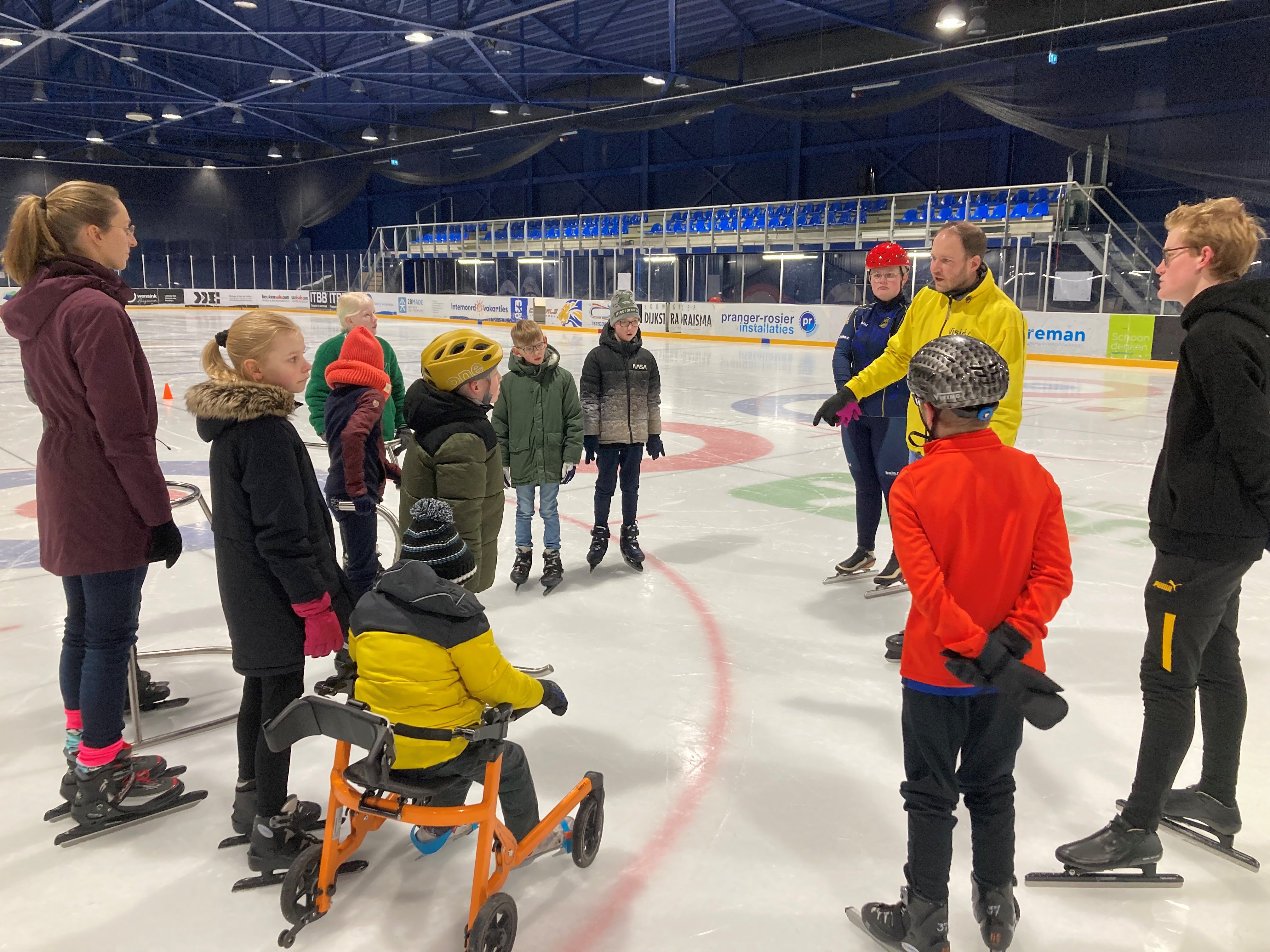 De kinderen krijgen uitleg van een schaatstrainer Kinderen krijgen uitleg